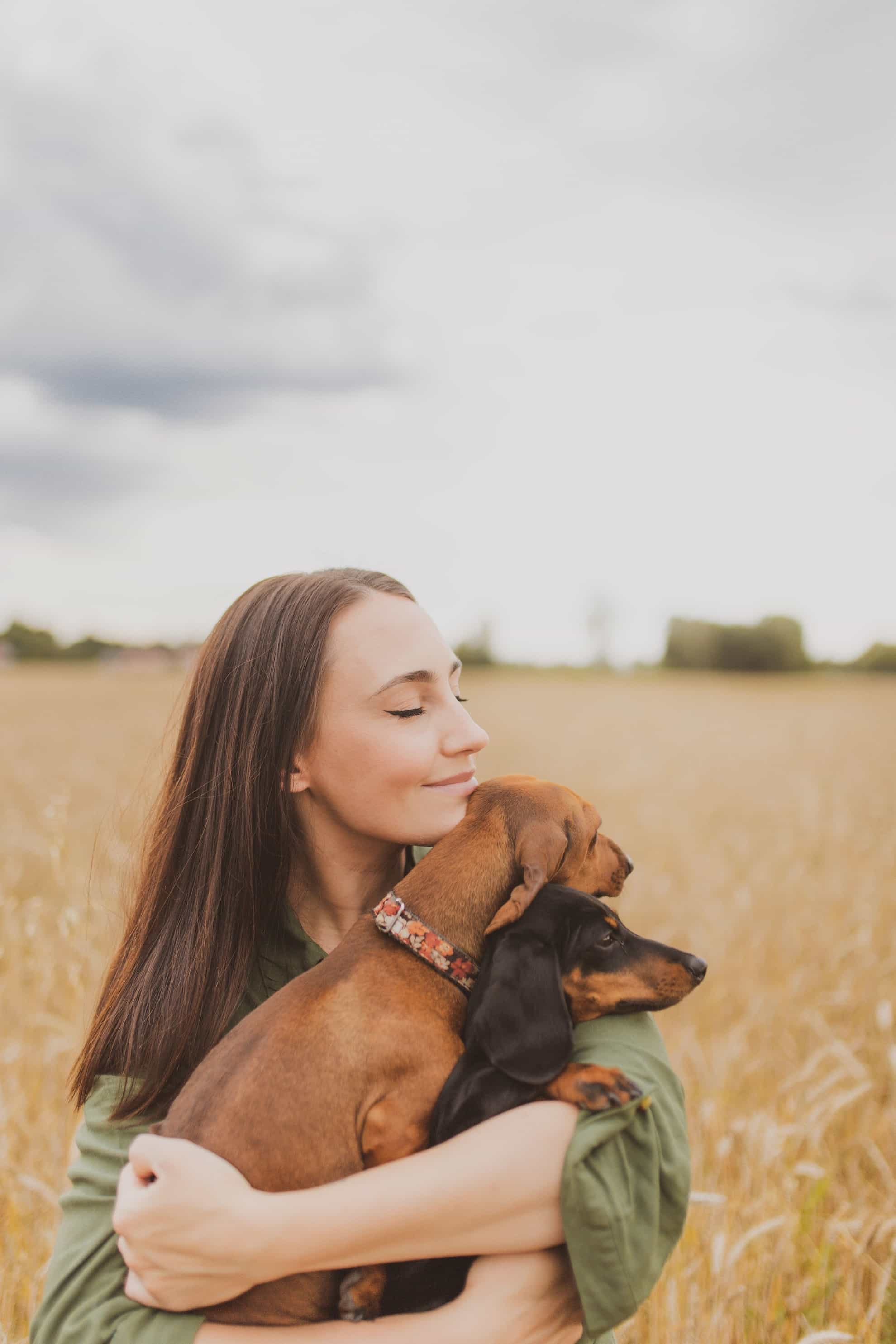 woman holding two happy dogs